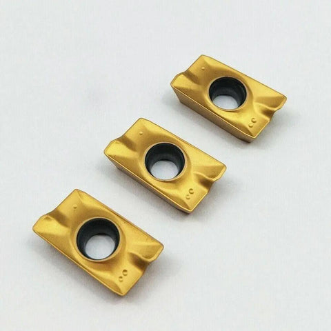 Close-up of three carbide inserts for CNC milling and turning tools APMT1604PDER, multilayer coated for hard steel machining.
