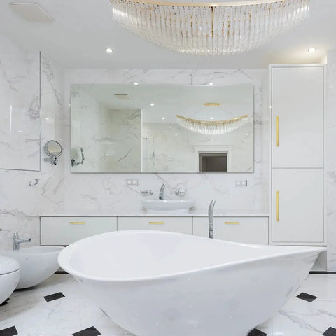 Luxurious marble bathroom with modern fixtures and white freestanding bathtub under a crystal chandelier
