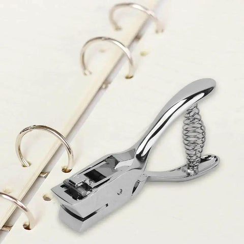 All Metal Handheld Hole Slot Puncher For ID Cards And Paper Crafts With 5.4 Inch Oval Punch And Spring Mechanism next to notebook