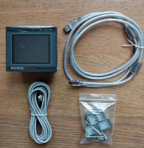 All In One PLC HMI with 2.8 inch touch screen display, seven input five relay outputs, four transistor outputs for 100KHz, FX1S compatible unit with cables and mounting hardware on wood surface.