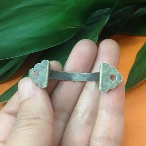 Close-up of antique brass zinc alloy mini jewelry box drawer cabinet pull handle from 10 pack, held in hand, vintage look, with 38mm hole spacing.