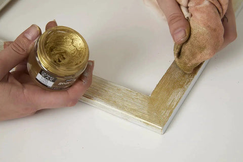 Applying Gilding Wax King Gold Metallic Paste For Furniture, Plaster, Glass, Metal And Paper to a wooden frame with a cloth.
