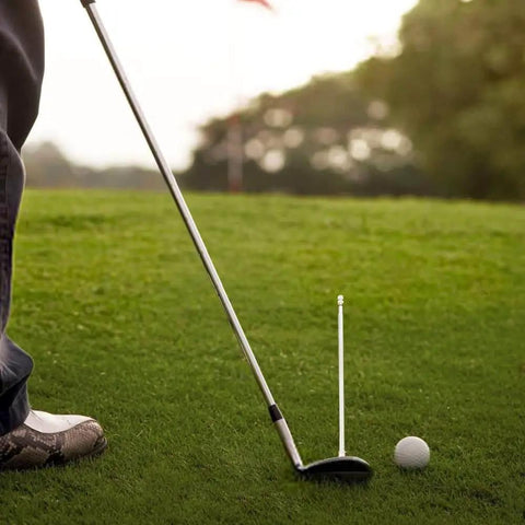 Golfer using Golf Alignment Rods Swing Trainer Aid for Consistent Golf Shots with a club and ball on a grassy course.