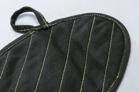 Close-up of X Pad Suppressor Handler in black with DuPont Kevlar stitching, CarbonX heat resistance up to 2000°F for tactical duty gear.