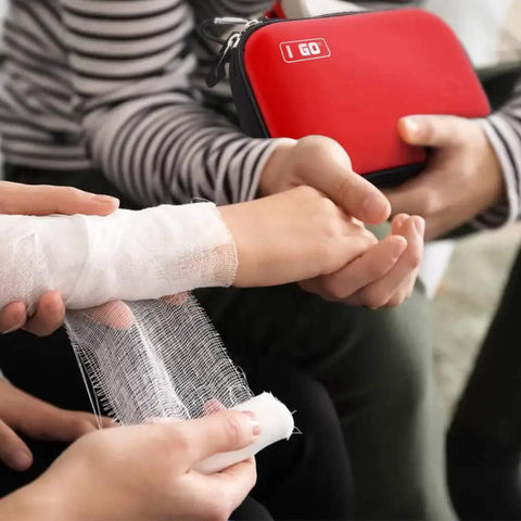 Using the 85 Piece Hard Shell Mini Compact First Aid Kit For Grab And Go Travel And Outdoor Adventures on an injured arm, with red case visible
