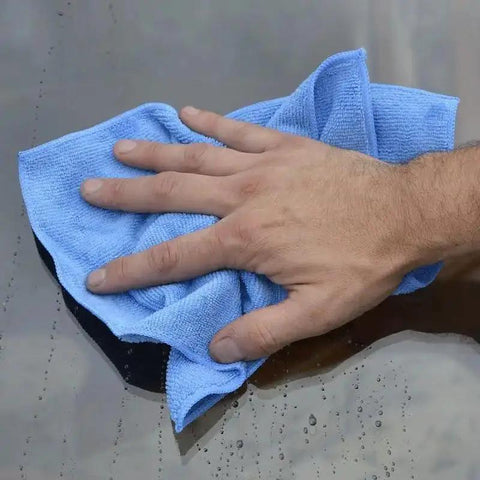 Hand using blue microfiber detailer cloth 12 pack 12 by 16 inch ultra absorbent pro grade polishing rags for car detailing