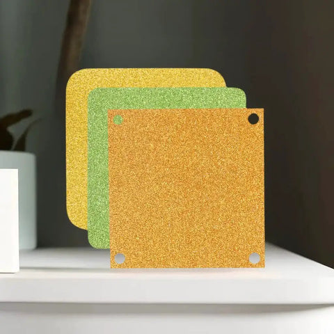 Sparkling cardstock sheets in gold, green, and yellow displayed on a shelf, ideal for die cuts and scrapbooking projects.