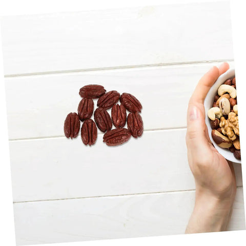 Realistic Walnut Miniature Pecans Set Ten Pieces For DIY Decor And Fake Food Props on a white tabletop with a hand holding mixed nuts.