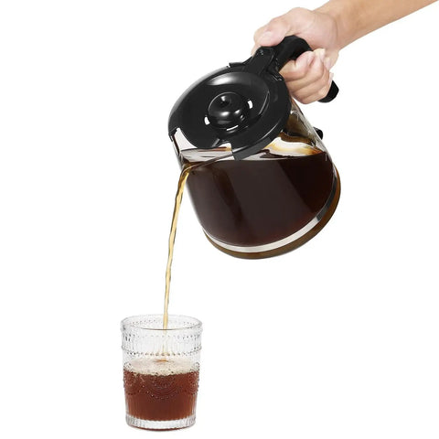Angled front view of a 12-cup glass coffee carafe with black lid pouring coffee.