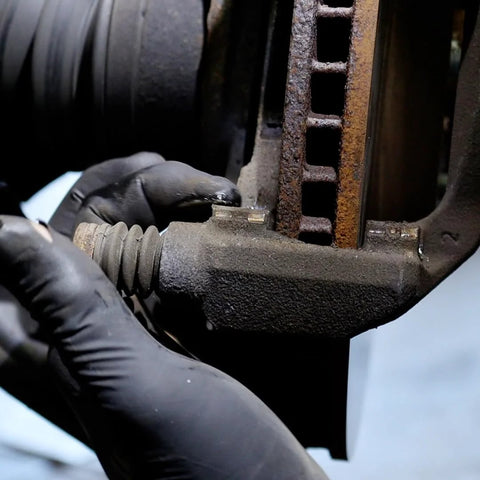 AGS SIL-Glyde silicone-based brake lubricant applied to a caliper slide pin by gloved hand