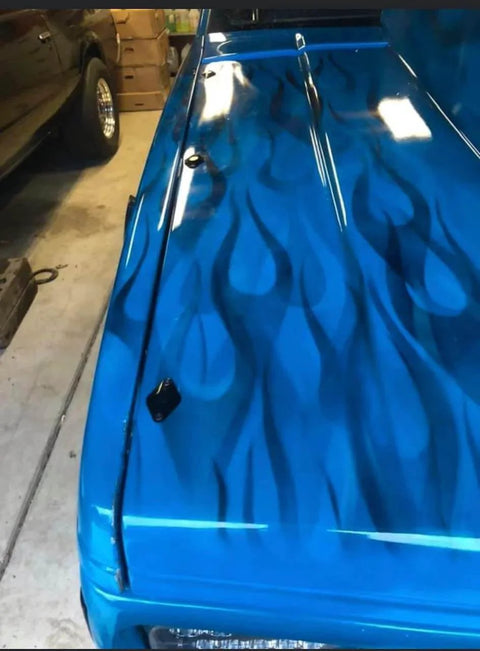 Blue truck hood with flame design in garage setting.