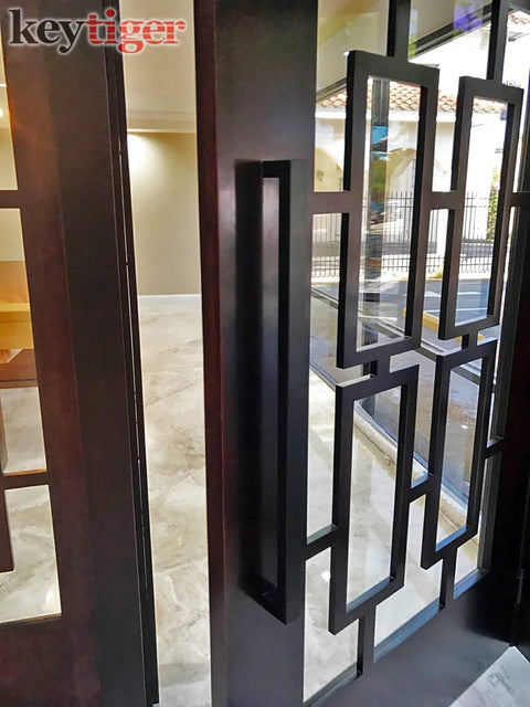 24 Inch Back To Back Modern Stainless Steel Door Handle Set In Matte Black Finish For Interior And Exterior Doors, installed on glass door.