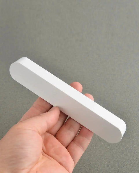 Hand holding one piece from 5 Pack Matte White Cabinet Handles For Kitchen Cabinets And Furniture Modern Drawer Pulls Center To Center Five Inches Length Five Point Nine Inches Width About One Inch Ideal For Kitchen Cabinets Bathroom Vanities Dressers And Closets