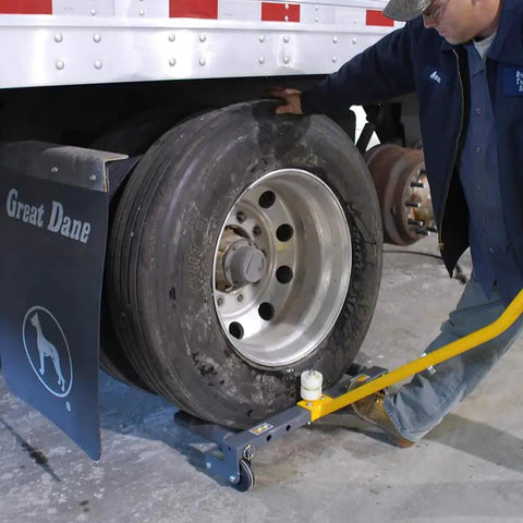 WINNTEC rolling wheel dolly in use under a large trailer tire; yellow lift bar and steel frame