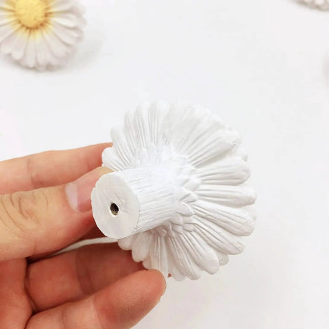 Hand holding Daisy Design Vintage Resin Drawer Pull, showcasing hand-painted white resin, for country kitchen cabinets.