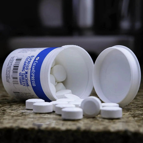Front view of CleanEspresso cleaning tablets bottle spilled on countertop with white round tablets