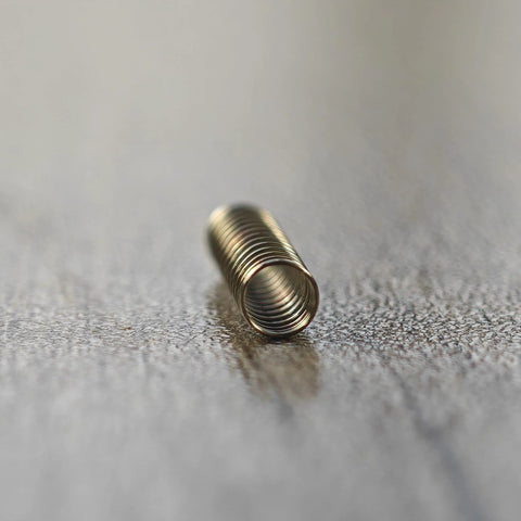 Close-up of stainless steel Cherry MX spring, replacement part for keyboard switches.