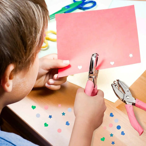 Child using Three Piece Hole Punch Set With Circle Heart And Star Shapes Includes One Quarter Inch And Three Sixteenths Inch Metal Body Soft Grip Handle for paper crafts.