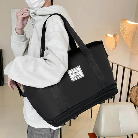 Rolling Duffle Bag With Detachable Wheels For Travel, Black travel tote with easy grab handles. Person carrying expandable weekender luggage shown.