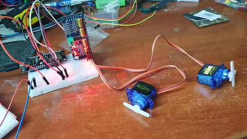 PCA9685 16 Channel 12 Bit PWM Servo Driver Board with I2C interface connected to servos for Raspberry Pi projects on a wooden table