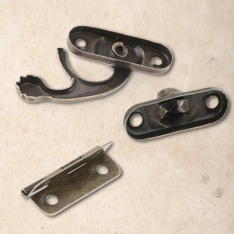 Close-up of Vintage Style Mini Swing Arm Clasp Latch Set With Dope Bronze Hinges and Antique Box Latch Hasp Lock parts on a table
