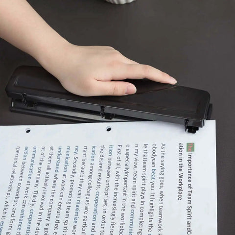 Person using Three Hole Punch For Home Office With Easy Clean Tray Punches Up To 10 Sheets At Once Durable Metal Construction Sleek Black Finish