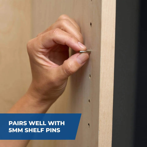 Hand placing shelf pin into wood with 5mm holes drilled using Pro Grade Shelf Hole Jig For Clean Wobble Free Shelves With Six Hardened Steel Drill Guides, Five Mm Hole Size, Increments Of One And A Quarter Inches, And A 32 Mm System, Durable Diy Woodworking Tool For Precise Shelving Installations