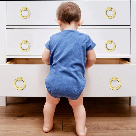 Child interacting with a dresser fitted with 4 Pack Gold Cabinet Knobs With Screws, Brushed Gold Ring Pulls For Dresser, Cupboard And Wardrobe.