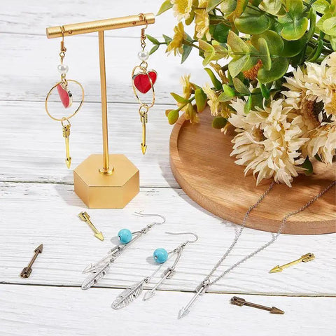 Arrowhead Charms 60Pcs Set In Gold Silver Bronze Three Colors Tibetan Style Alloy Double Sided Miniature Charms For Jewelry Making And DIY Crafts Necklace Earrings Keychain displayed on a table.