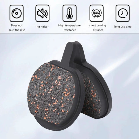 Close-up view of two round bicycle disc brake pads with copper-speckled friction surface in black housings