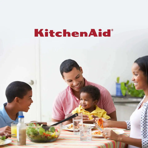 Happy family enjoying meal at dining table with KitchenAid branding.