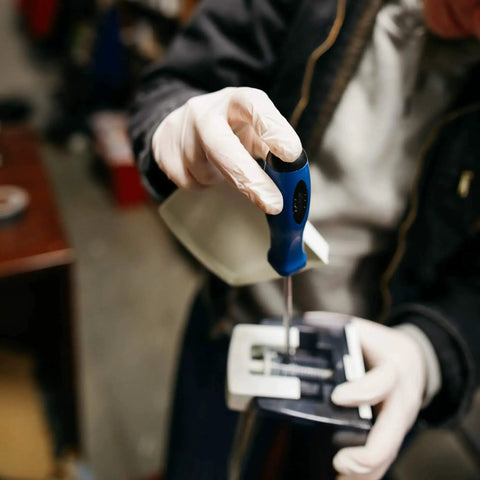Person using screwdriver while wearing industrial grade latex disposable gloves 8 mil powder free double chlorinated case of 1000