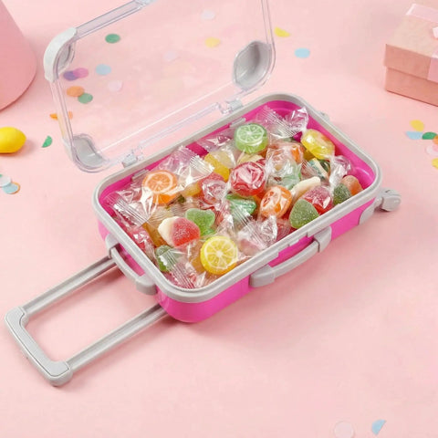 4 Pack Mini Suitcase Party Favor Boxes with clear lids, extendable handles, and wheels filled with colorful candies on a pink background.