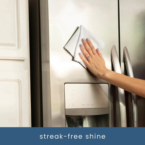 Person using Two 50-Pack Microfiber Cleaning Cloths in Boxes 11.8x11.8 White 190gsm on a stainless steel fridge