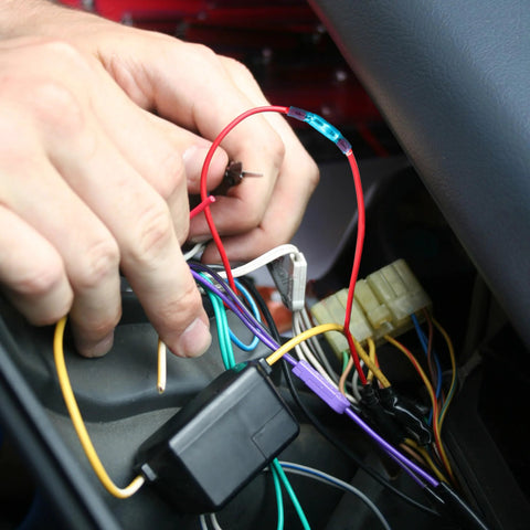 Heat shrink butt connectors with blue sleeves being crimped onto a red automotive wire in a car wiring harness.