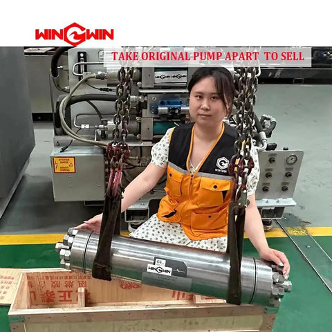 Person sitting next to a waterjet pump intensifier with industrial equipment in the background.