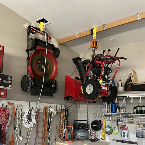 Lifting straps hanging from a ceiling beam in a garage, yellow nylon webbing used with a hoist.