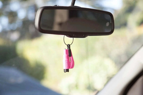 Pink keychain of Pack Of 2 Emergency Car Escape Tools With 2 In 1 Seatbelt Cutter And Window Breaker hanging on rearview mirror in car.