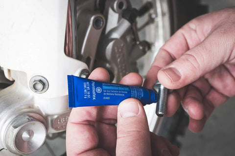 Blue Medium Strength Thread Locker For Bolts And Fasteners Quarter Inch To Three Quarter Inch Keeps Vibration From Loosening Seals Leaks And Corrosion Removable With Hand Tools 36 Milliliters being applied to a bolt.
