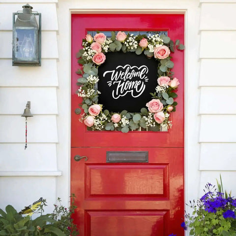 Red front door with 'Welcome Home' sign surrounded by floral wreath