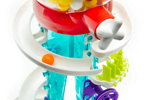 Thames and Kosmos Gumball Machine Maker toy, close-up with red top, blue transparent body, yellow gears, and orange ball.