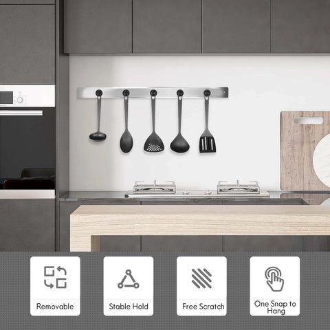 Modern kitchen with wall-mounted utensil holder, four black cooking utensils hanging above a counter, focus on minimalist design and functionality.