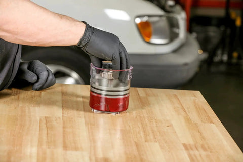 Two Piece Deluxe And Standard Bearing Packer Kit used for quick flushing and repacking of wheel bearings with red grease, on workbench