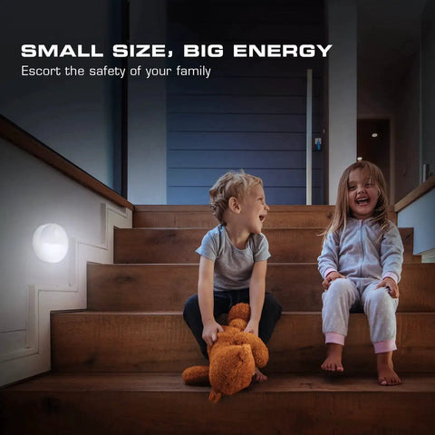Two children sitting on stairs with a Motion Sensor Night Light With Auto On Off, No Fuss Cool White LED Path Light on the wall