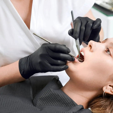 Dentist wearing nitrile exam gloves latex free powder free disposable for medical use treating patient's teeth