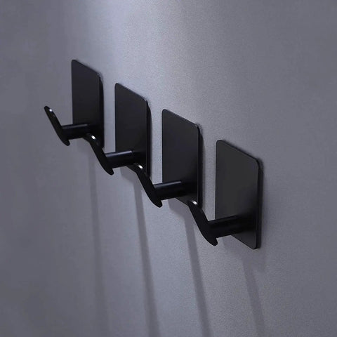 Matte black adhesive hooks 4 pack on wall, ideal for towels, coats, kitchen use. Adhesive Hooks 4 Pack Towel And Coat Hooks For Wall Mounting.