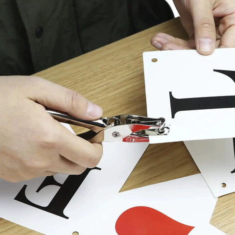 Person using 24 Pack One Quarter Inch Single Hole Puncher Set With 5 Sheet Capacity, Metal Construction, Built In Confetti Storage on paper.