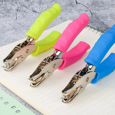 12 Piece Multicolor Single Hole Puncher Set, Quarter Inch Metal Handheld Circle Punch With Soft Grip displayed on notebook