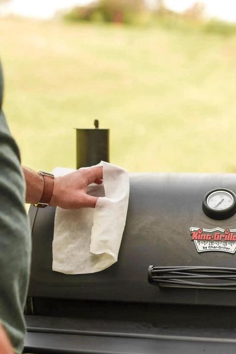 Person using Plant Based Grill Cleaning Wipes Aloe And Vitamin E Safe On Surfaces Large 15X10 on a grill lid.