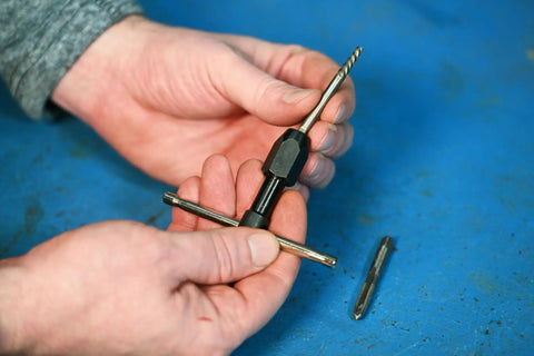 Hands holding T-Handle Tap Wrench For Quarter To Half Inch Taps Steel Construction Precise Control Easy Install And Firm Grip